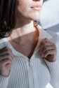 Person wearing a gold necklace with a blurred background