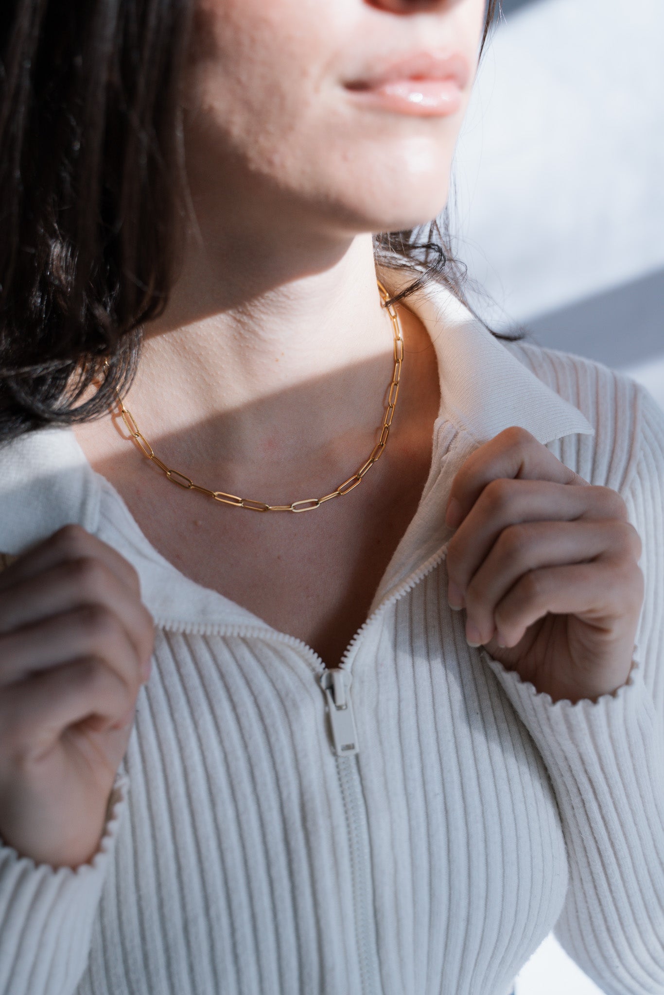 Person wearing a gold necklace with a blurred background