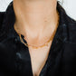 Close-up of a person wearing a gold necklace and earrings against a white background
